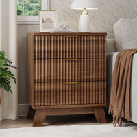Linea modern walnut fluted 3-drawer nightstand with gold metal handles, styled with a white lamp and framed art by a window.