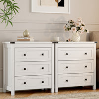 Two white farmhouse nightstands with 3 drawers side by side in living room styled with flowers and books