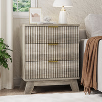 Linea modern gray fluted 3-drawer nightstand with gold metal handles, styled with a white lamp and framed art by a window.
