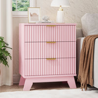 Linea modern pink fluted 3-drawer nightstand with gold metal handles, styled with a white lamp and framed art by a window.