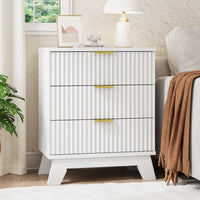 Linea modern white fluted 3-drawer nightstand with gold metal handles, styled with a white lamp and framed art by a window.